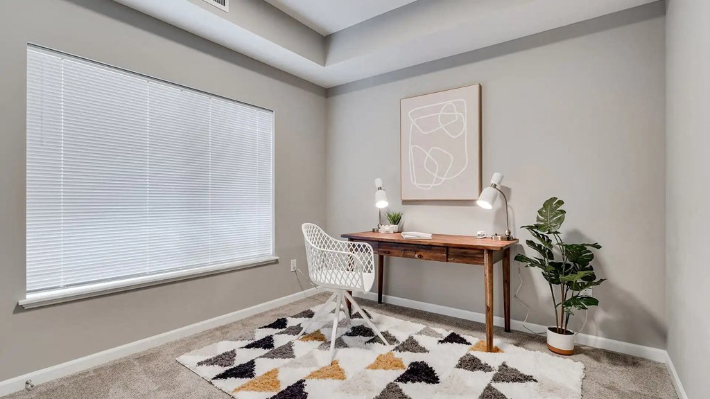 a home office with a large window and a desk with a chair. Circle Pines, MN Lexington Lofts
