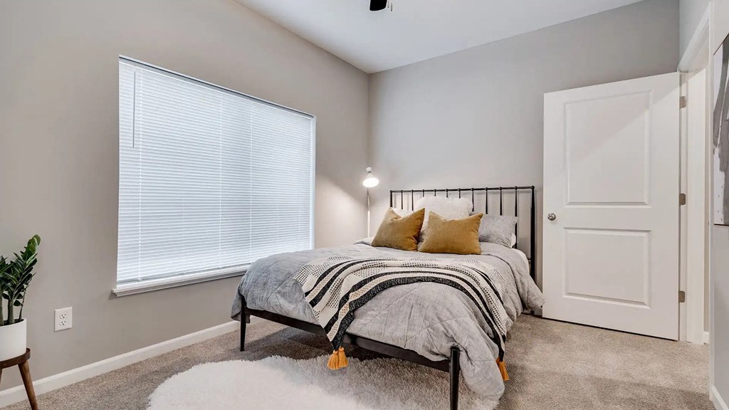 a bedroom with a bed next to a window. Circle Pines, MN Lexington Lofts
