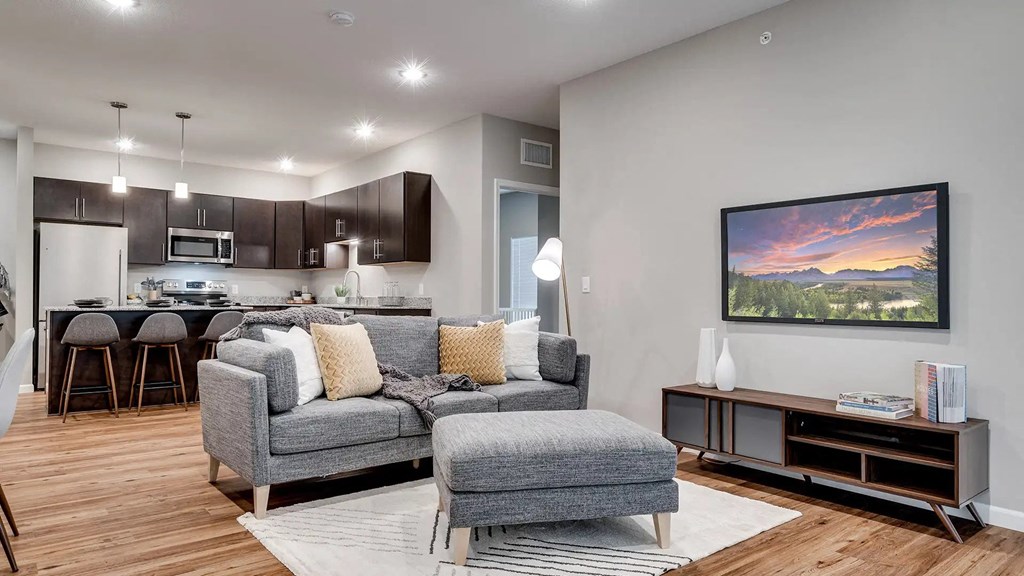 a living room with a couch and a chair in front of a kitchen. Circle Pines, MN Lexington Lofts