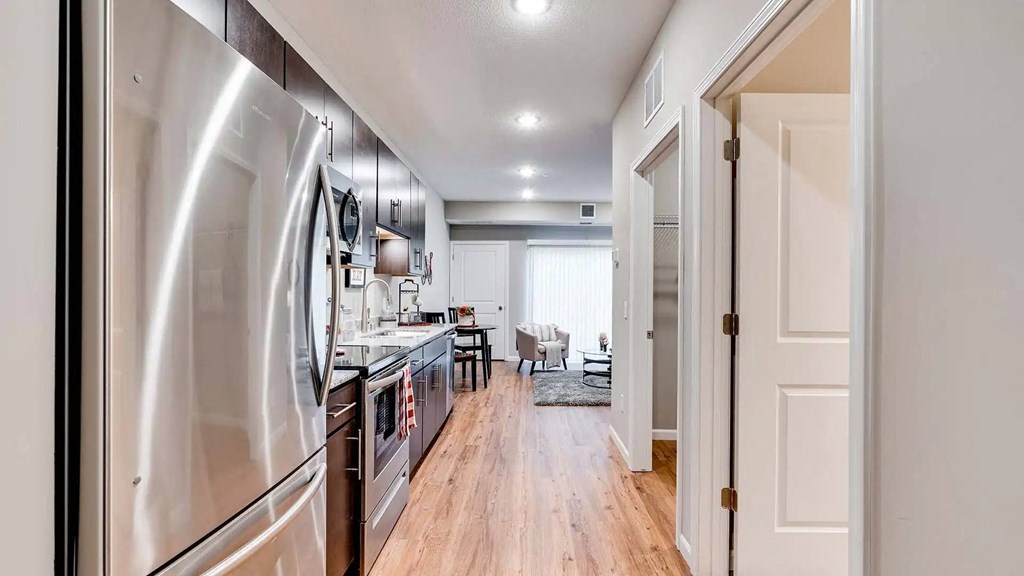 a kitchen with stainless steel appliances and a door to a living room. Circle Pines, MN Lexington Lofts