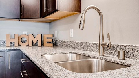 A kitchen with a sink and a wooden HOME sign.