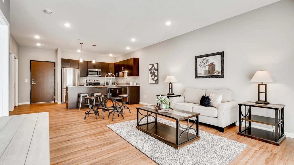 a living room with a couch and a table in front of a kitchen. Circle Pines, MN Lexington Lofts
