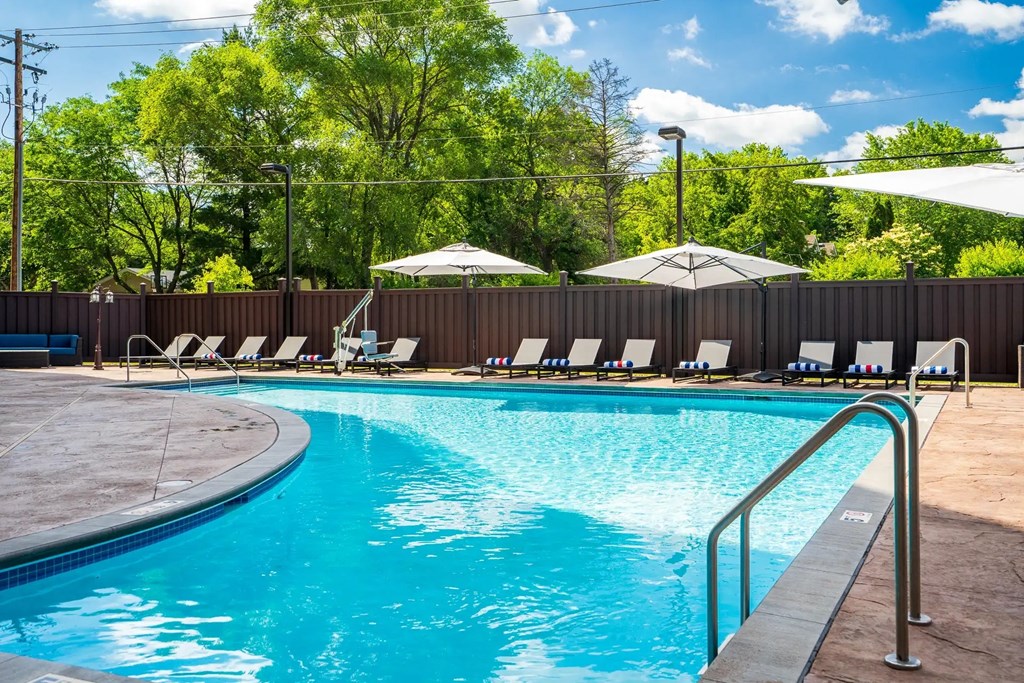 a swimming pool with chairs and umbrellas. Circle Pines, MN Lexington Lofts