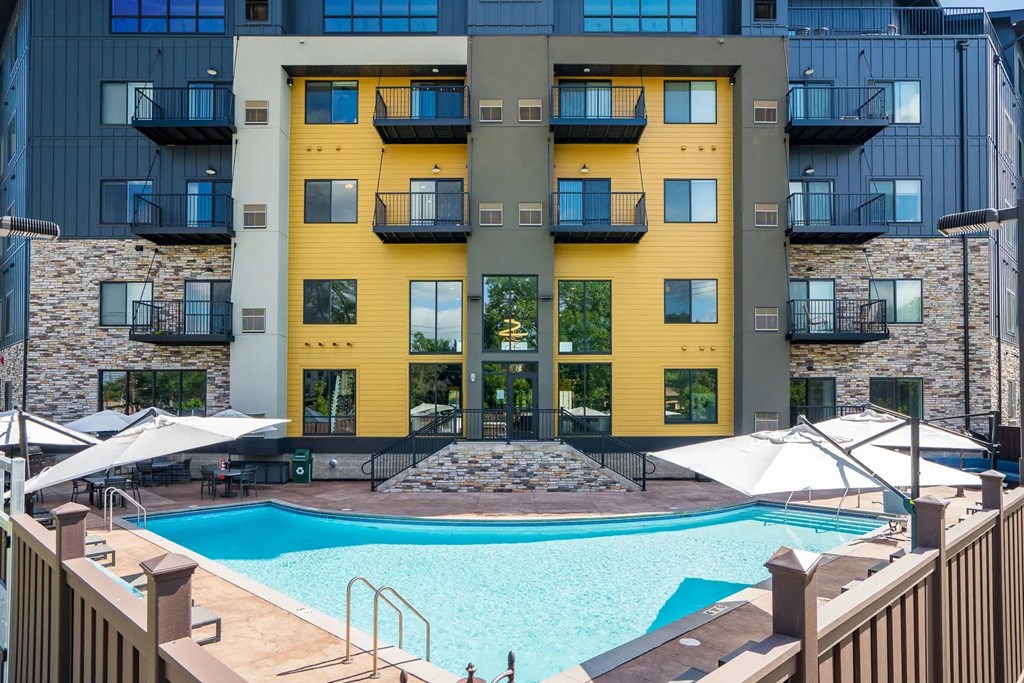 a swimming pool at an apartment building with a pool and umbrellas. Circle Pines, MN Lexington Lofts