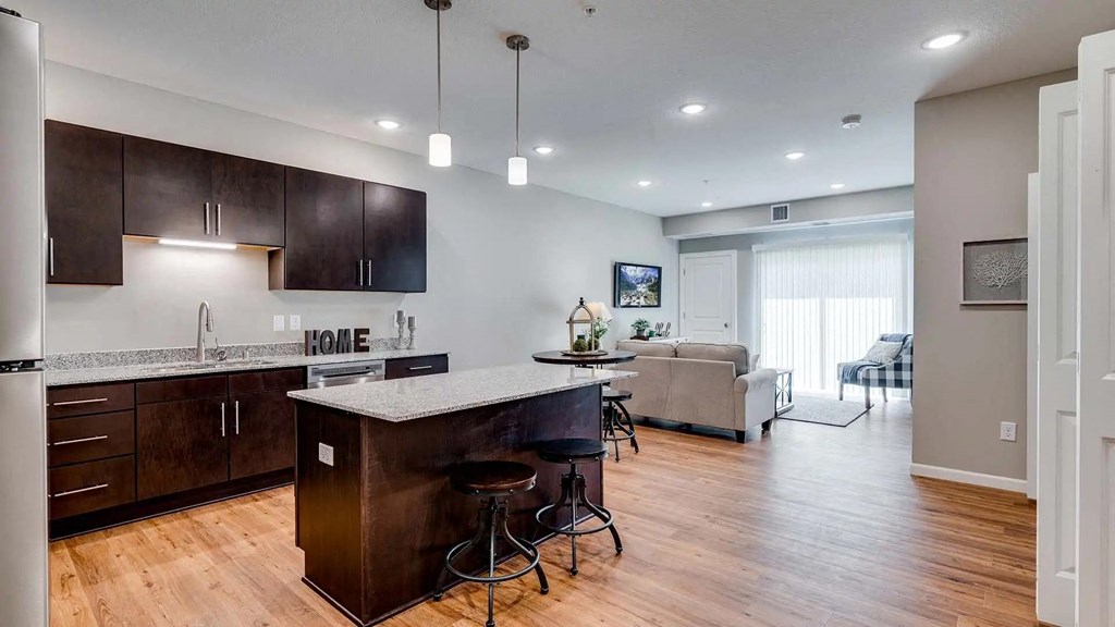 a kitchen with a bar and a living room with a couch. Circle Pines, MN Lexington Lofts