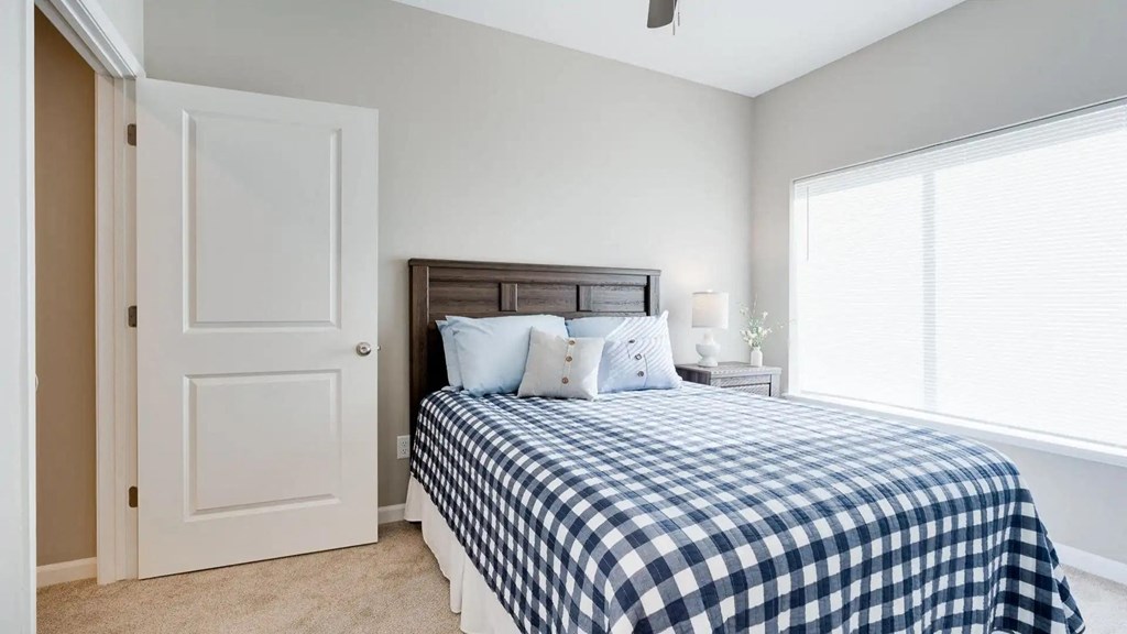 a bedroom with a bed and a large window. Circle Pines, MN Lexington Lofts