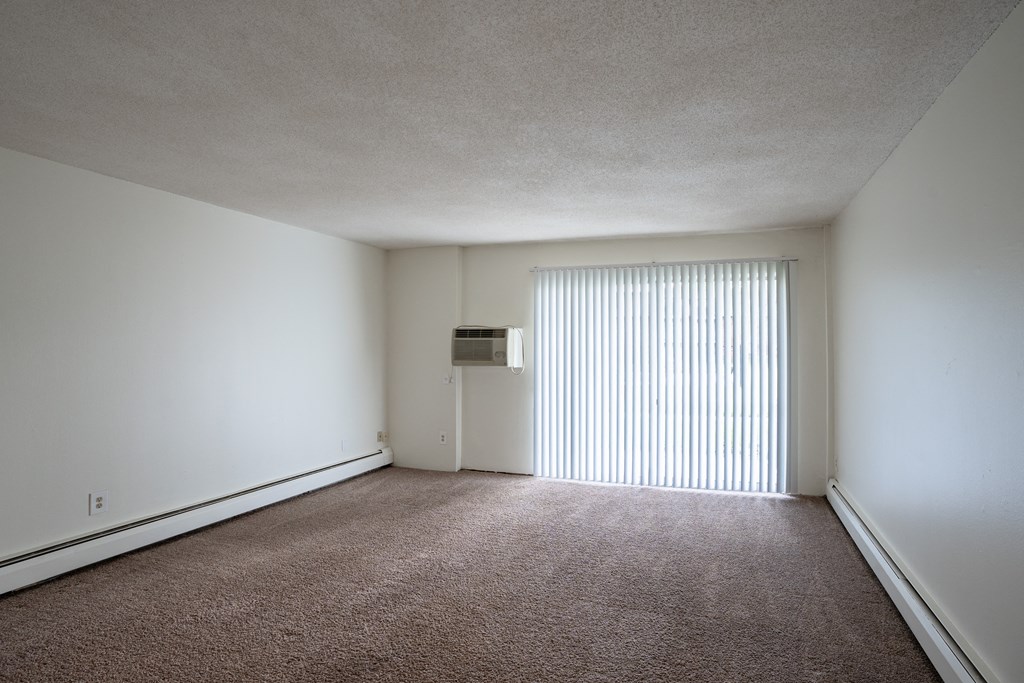 the living room of an apartment with a large window and white walls. Coon Rapids, MN Robinwood Apartments
