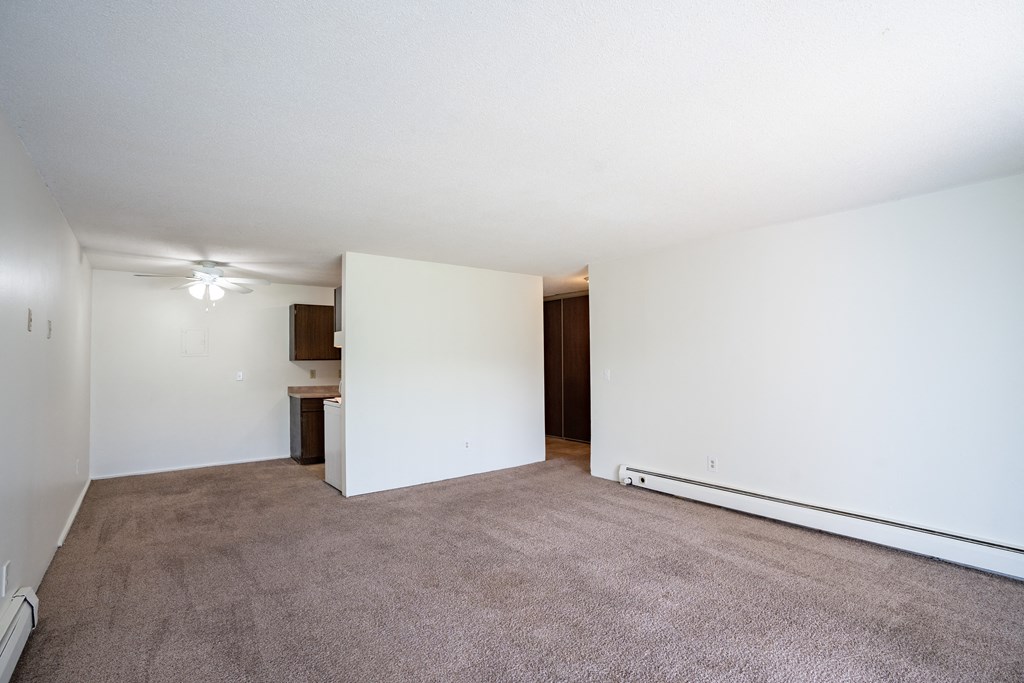 an empty living room with white walls and carpet. Coon Rapids, MN Robinwood Apartments