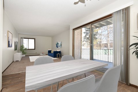a dining area with a white table and chairs and a sliding glass door leading to a patio