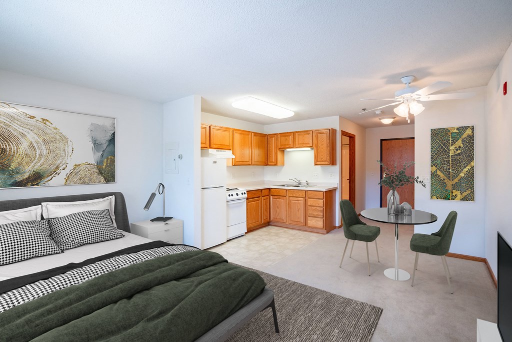 a bedroom with a bed and a kitchen with a table and chairs