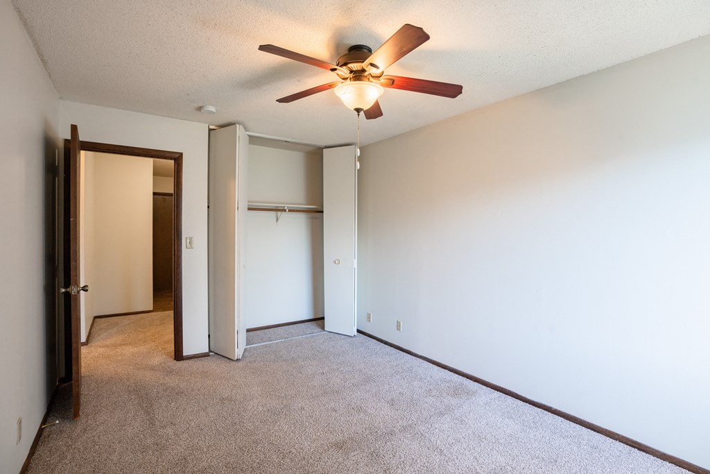 the living room of an empty apartment with a ceiling fan.   Eagan, MN Glen Pond Apartments