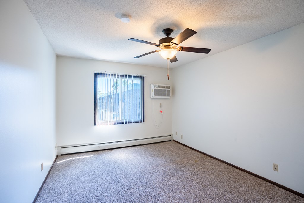an empty living room with a ceiling fan and a window.  Eagan, MN Glen Pond Apartments