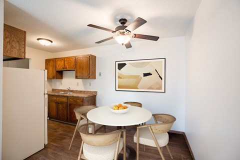 a dining area with a table and chairs and a kitchen with a refrigerator