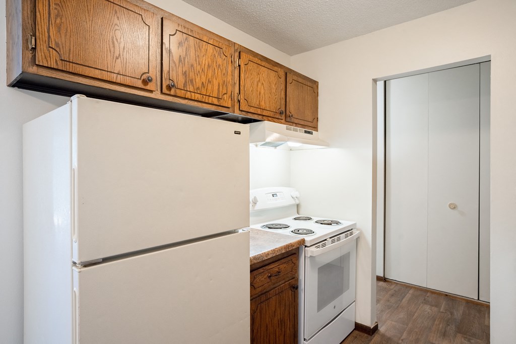 a kitchen with white appliances and wooden cabinets and a refrigerator.  Eagan, MN Glen Pond Apartments