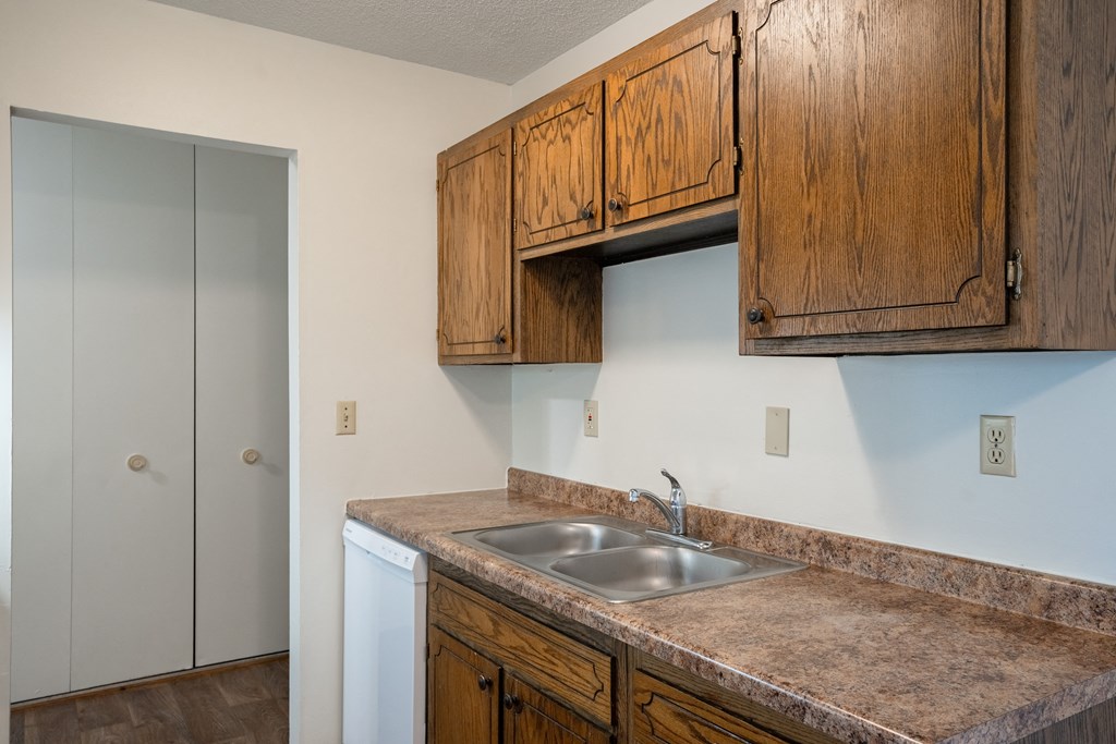 a kitchen with a sink and cabinets and a door to a closet.  Eagan, MN Glen Pond Apartments