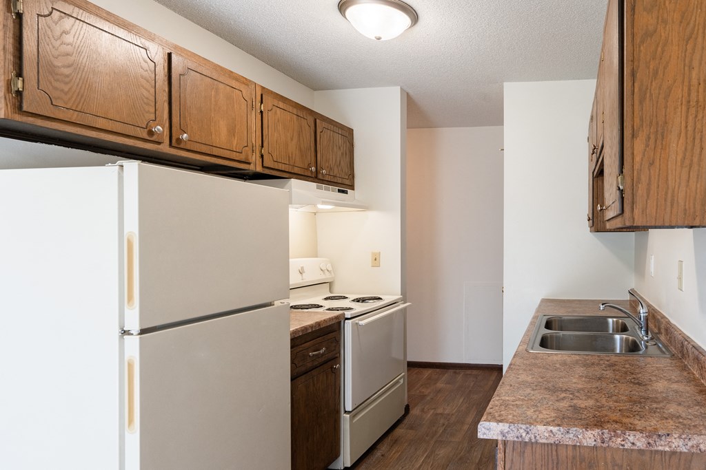 an empty kitchen with white appliances and wooden cabinets. Eagan, MN Glen Pond Apartments