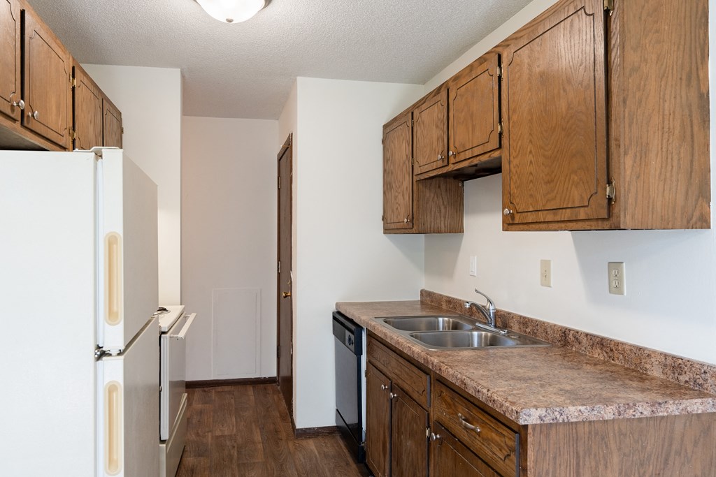 a kitchen with wooden cabinets and a sink and a refrigerator. Eagan, MN Glen Pond Apartments