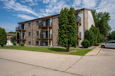 A large apartment building with balconies and trees in front. Fargo, ND Hawthorn Apartments