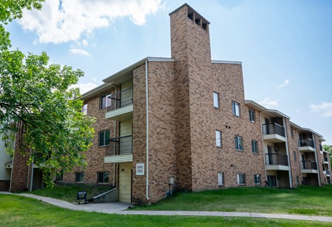 A brick building with a balcony and a small entrance. Grand Forks, ND Columbia West Apartments