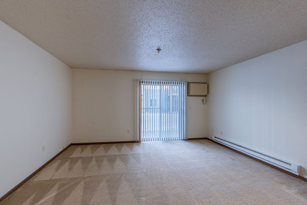 the living room of an empty apartment with a sliding glass door. Fargo, ND Lake Crest Apartments