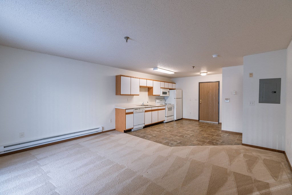an empty living room and kitchen with white walls and a tiled floor. Fargo, ND Lake Crest Apartments