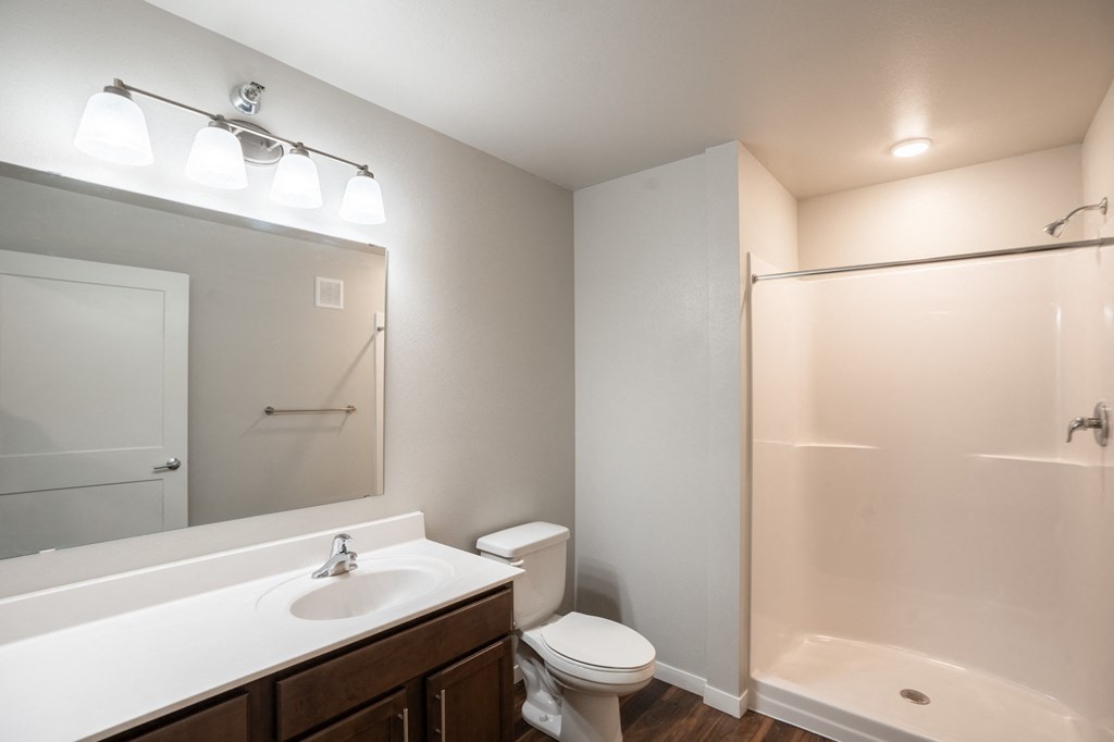 a bathroom with a large mirror and a toilet and a shower. Fargo, ND 29 West Apartments