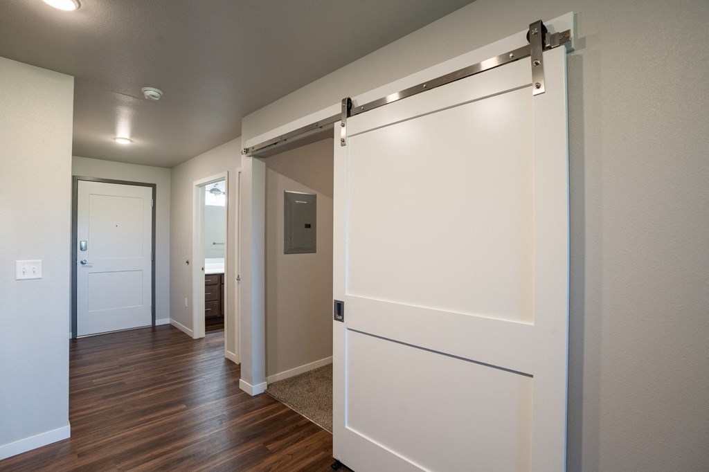 a bedroom with a white door and a hallway with a door to a bathroom. Fargo, ND 29 West Apartments
