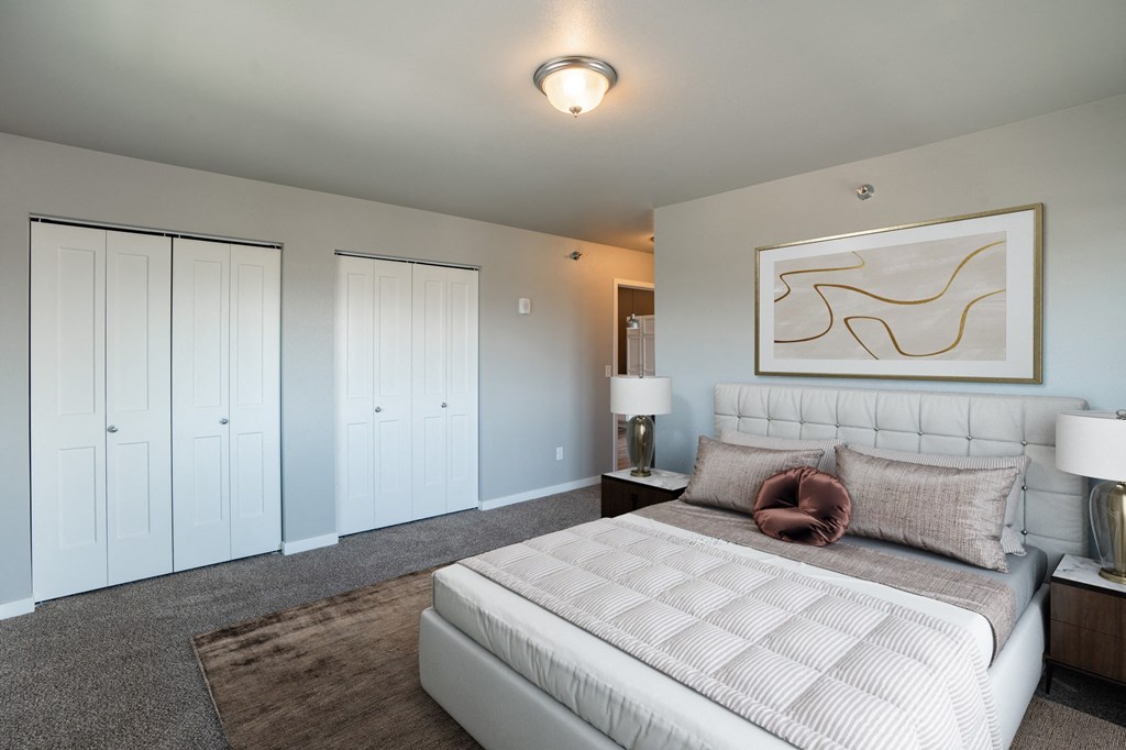 a bedroom with a large white bed and white closets. Fargo, ND 29 West Apartments
