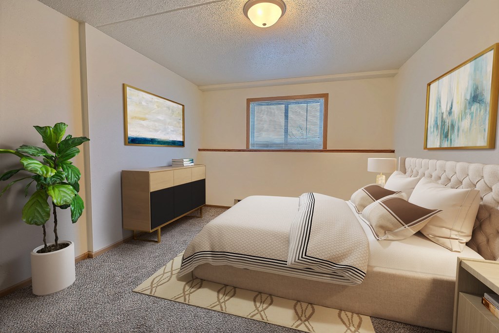 a bedroom with a bed and a potted plant. Fargo, ND Alden Pines Apartments