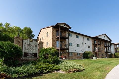Exterior of a three level apartment with a sign outside. Fargo, ND Auburn Apartments .