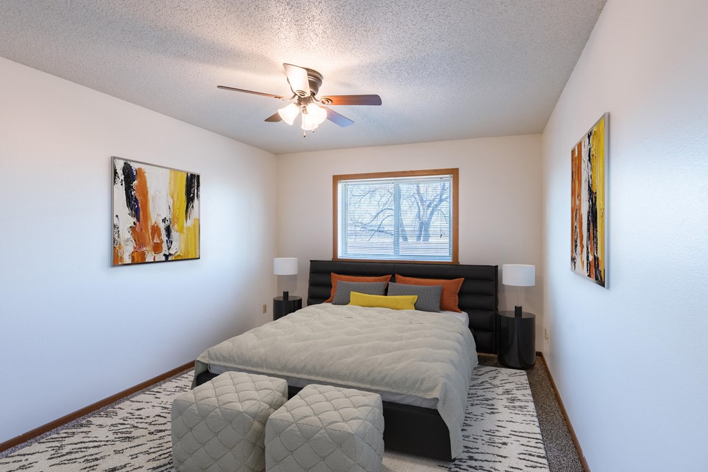 a bedroom with a large bed and a ceiling fan. Fargo, ND Auburn II Apartments