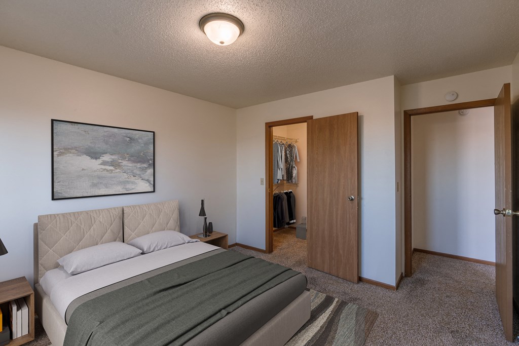 a bedroom with a bed and a closet. Fargo, ND Auburn II Apartments.