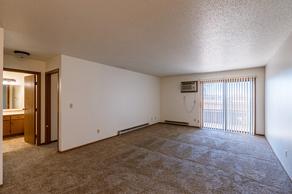 the living room of an empty apartment with a sliding glass door. Fargo, ND Auburn II Apartments