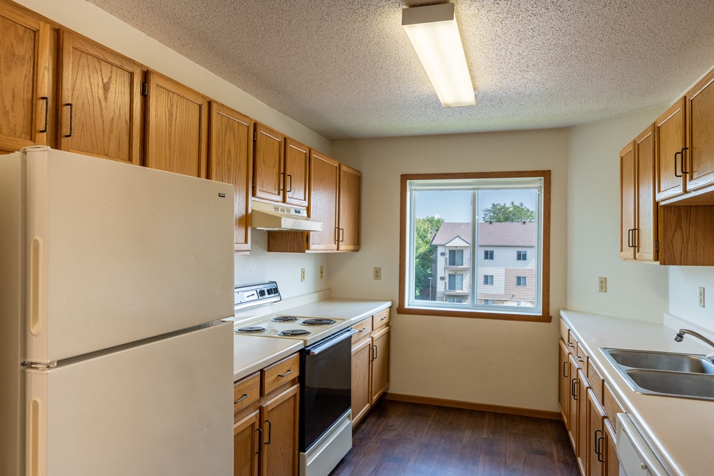 Fargo, ND Bayview Apartments. A kitchen with white appliances and wooden cabinets