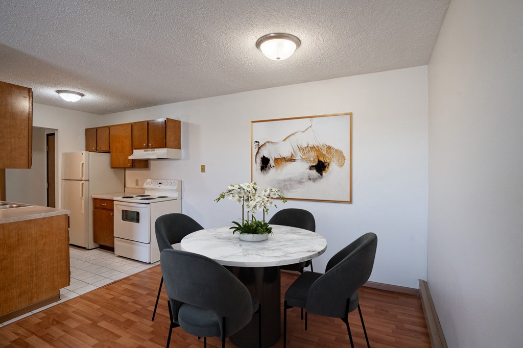 a dining room with a table and chairs and a kitchen. Fargo, ND Bella Vista Apartments