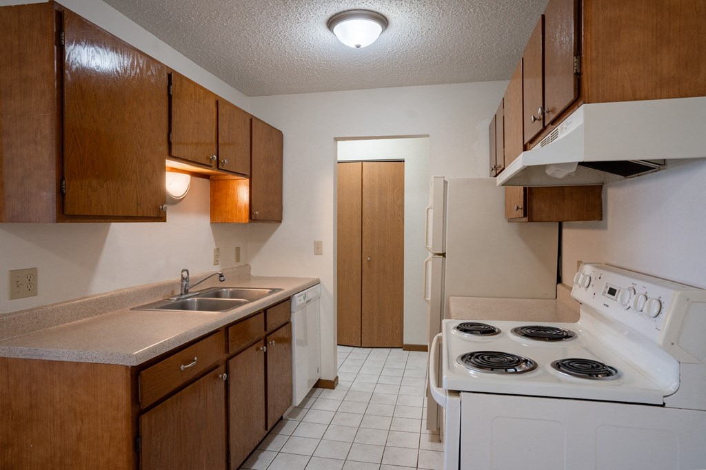 a kitchen with a stove and sink and a refrigerator. Fargo, ND Bella Vista Apartments