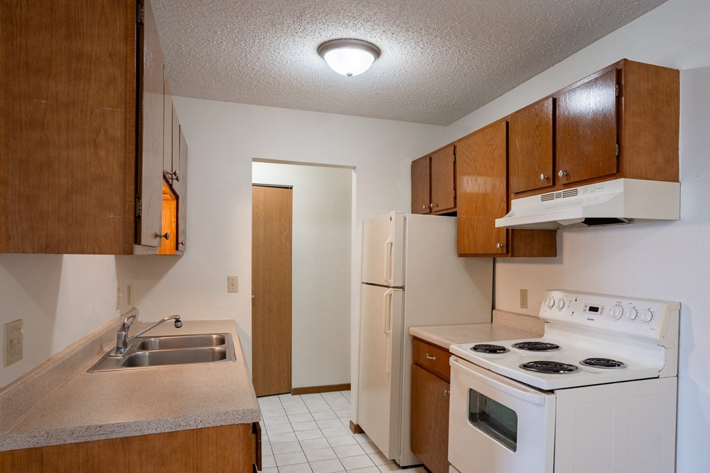 an empty kitchen with a stove refrigerator and sink. Fargo, ND Bella Vista Apartments