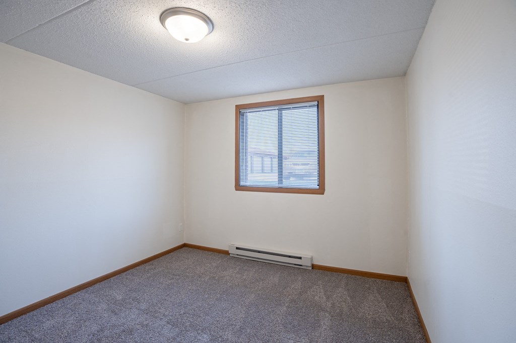 a bedroom of an empty house with a window. Fargo, ND Bella Vista Apartments