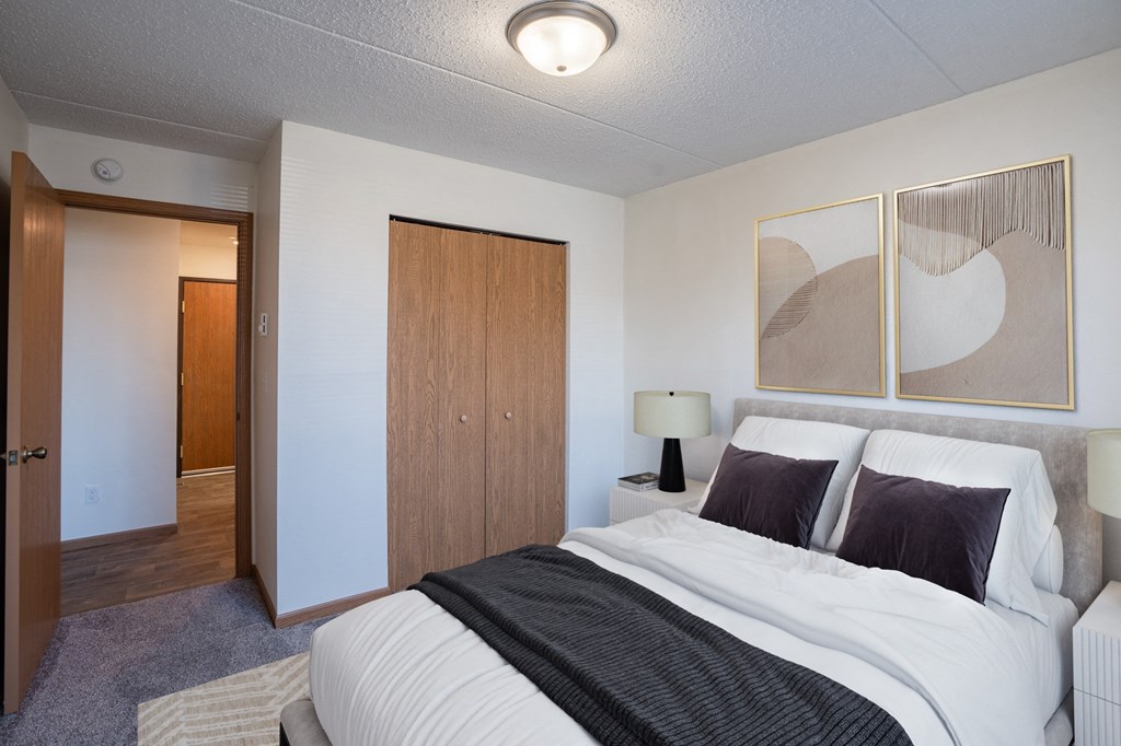 a bedroom with a bed and a closet and a door to a bathroom. Fargo, ND Bella Vista Apartments