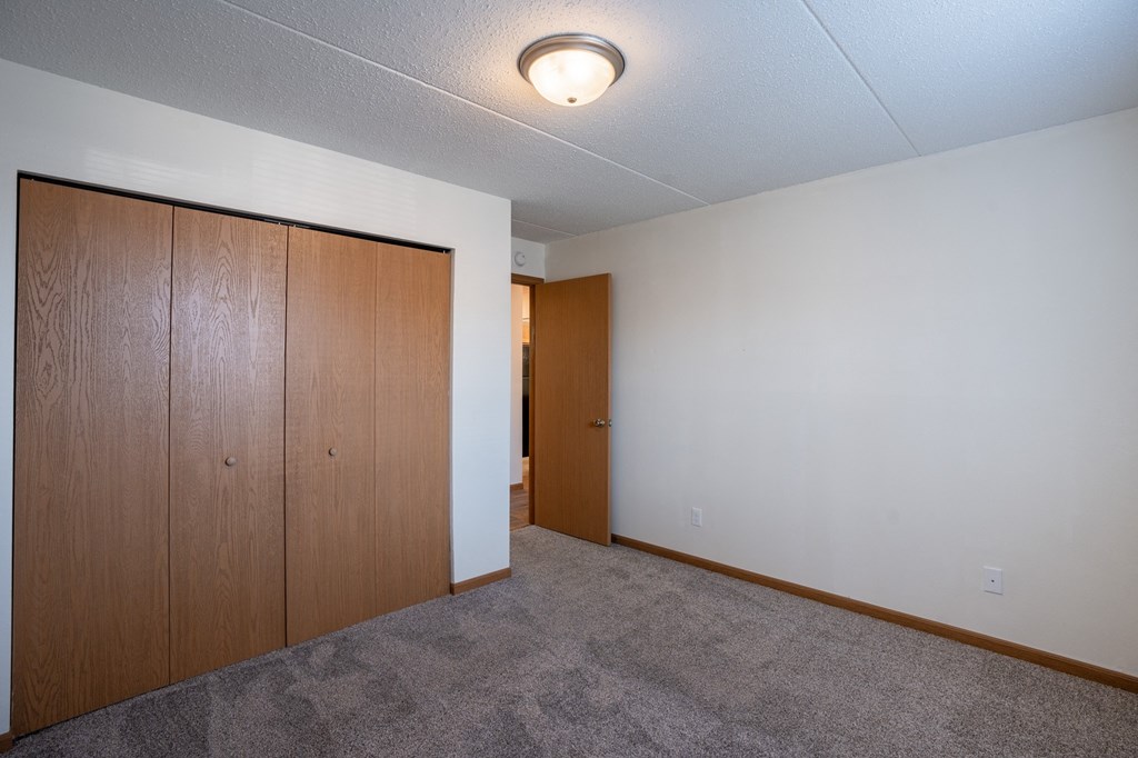 the living room of an empty apartment with a door to the hallway. Fargo, ND Bella Vista Apartments