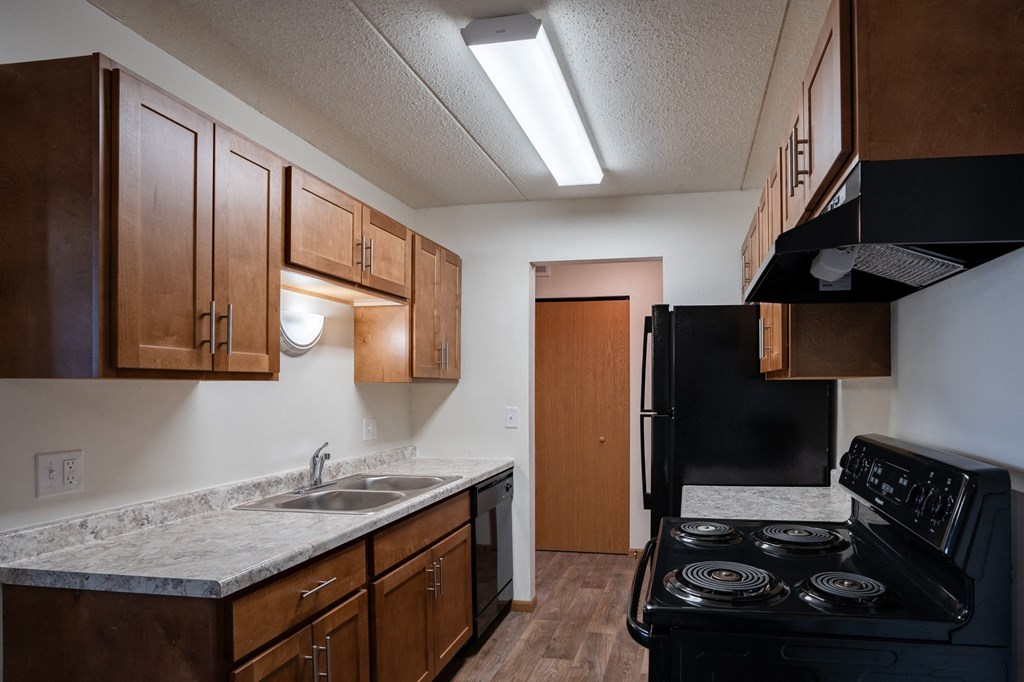 a kitchen with a stove and sink and a refrigerator. Fargo, ND Bella Vista Apartments
