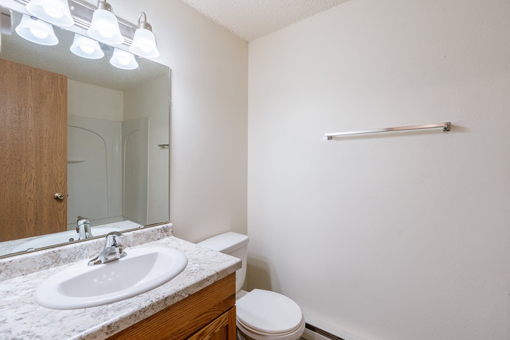 a bathroom with a sink and a mirror and a toilet. Fargo, ND Berkshire Apartments