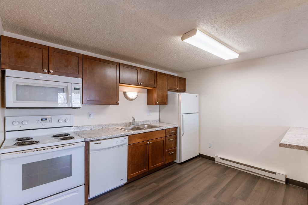 a kitchen with white appliances and wooden cabinets and a white refrigerator. Fargo, ND Berkshire Apartments