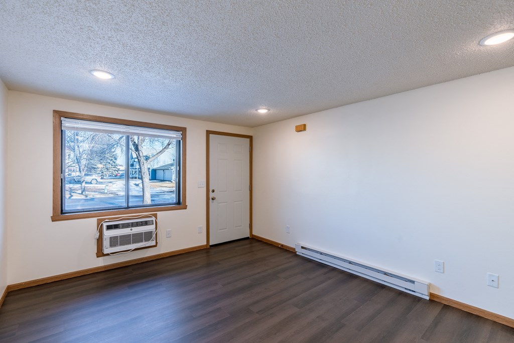 an empty living room with a window and a door. Fargo, ND Berkshire Apartments