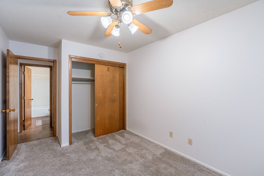 an empty bedroom with a ceiling fan and a door to a closet Fargo, ND Betty Ann Apartments