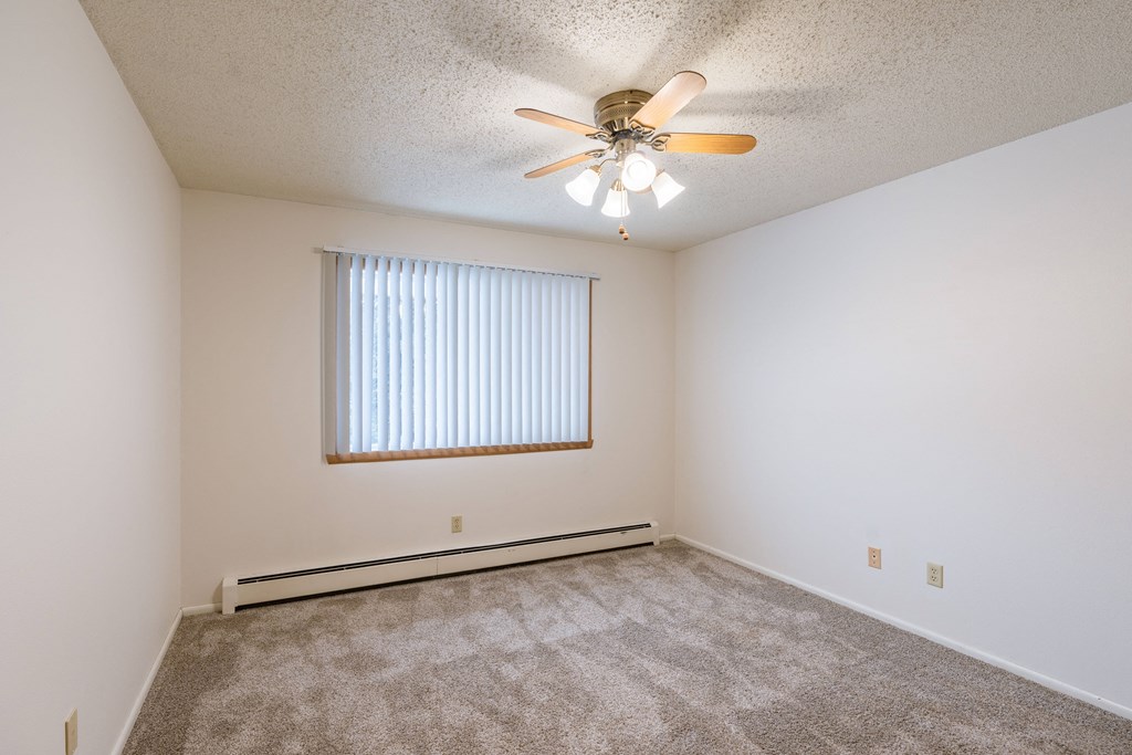 a bedroom with carpet and a ceiling fan. Fargo, ND Betty Ann Apartments