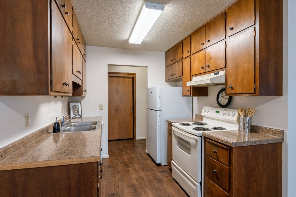 a kitchen with white appliances and wooden cabinets. Fargo, ND Betty Ann Apartments