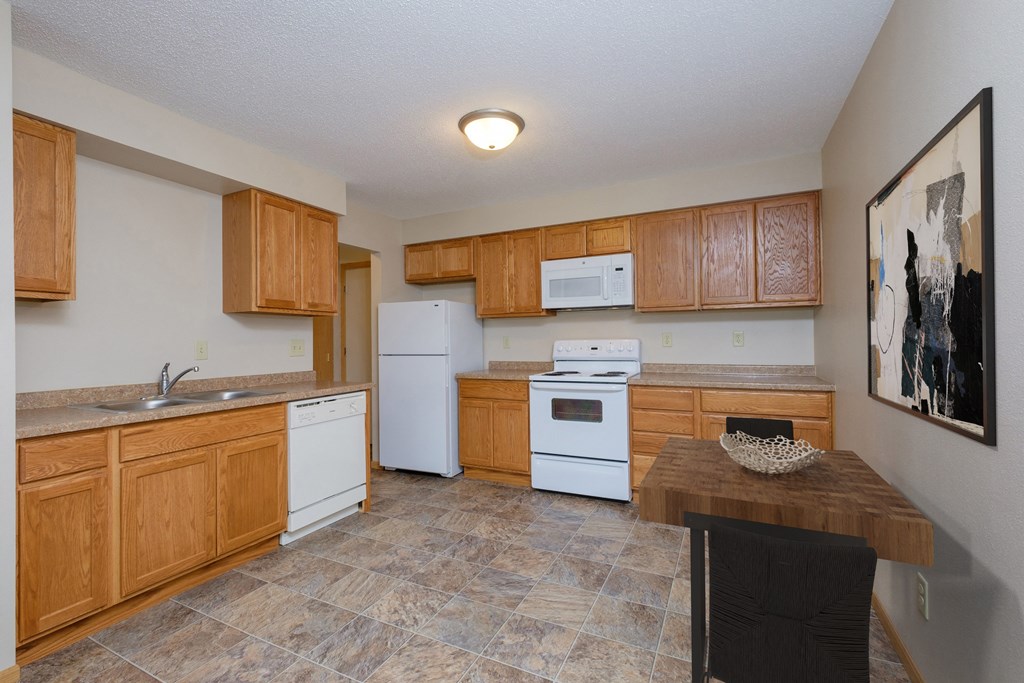 Fargo, ND Birchwood 2 Apartments | Kitchen a kitchen with white appliances and wooden cabinets. Fargo, ND Birchwood 2 Apartments
