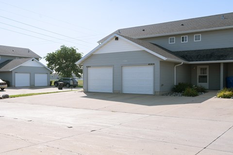 a white house with two garage doors and a driveway. Fargo, ND Bluestem Townhomes