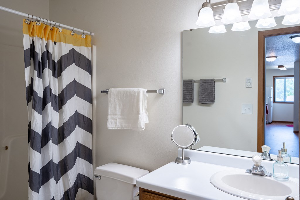 a bathroom with a black and white shower curtain. Fargo, ND Briar Pointe Apartments